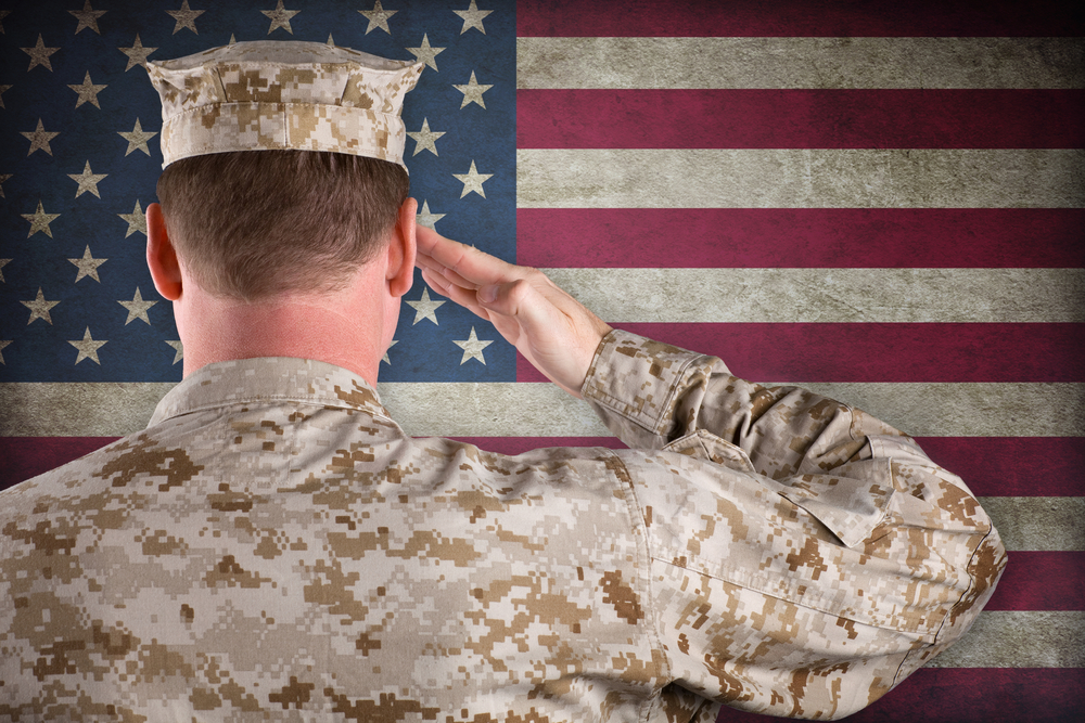 Soldier facing American flag and soluting